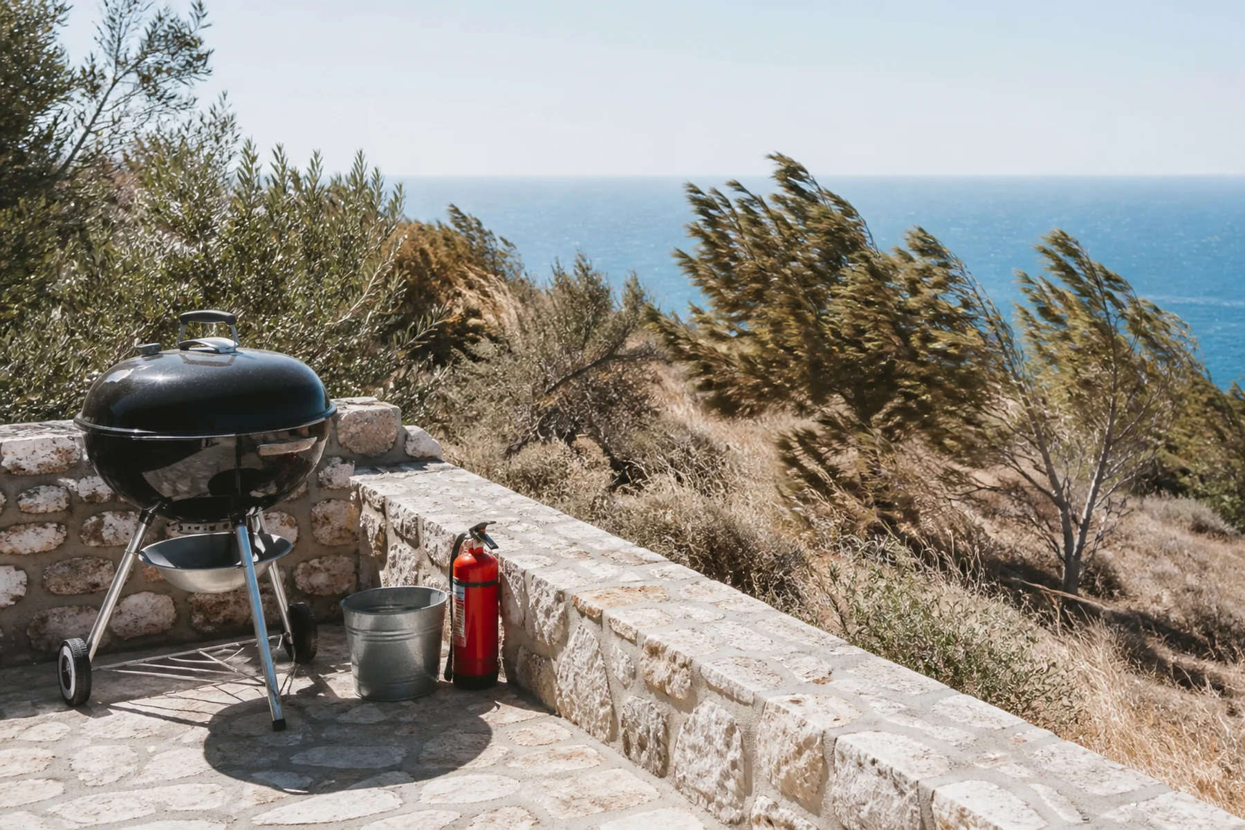 Geschlossener Grill mit Löschwasser an einer trockenen, windigen Adriaküste