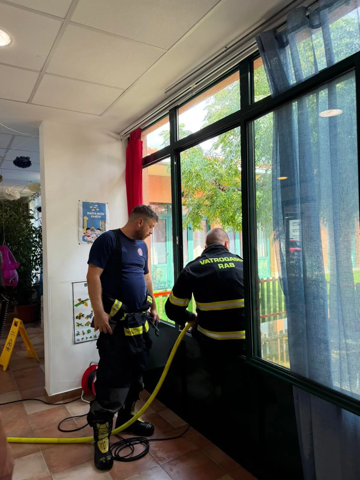 Zwei Feuerwehrleute des DVD Rab beim Abpumpen von Wasser im Kindergarten Pahuljica auf Rab