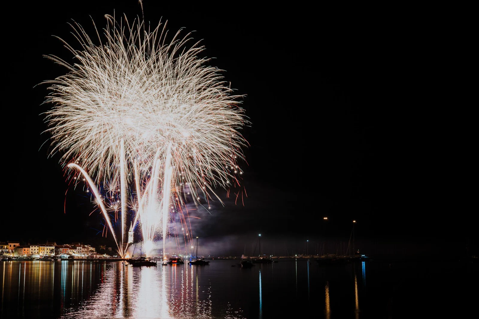 Feuerwerk der Fešta sv. Pelagija über dem nächtlichen Hafen und der Altstadt von Novigrad