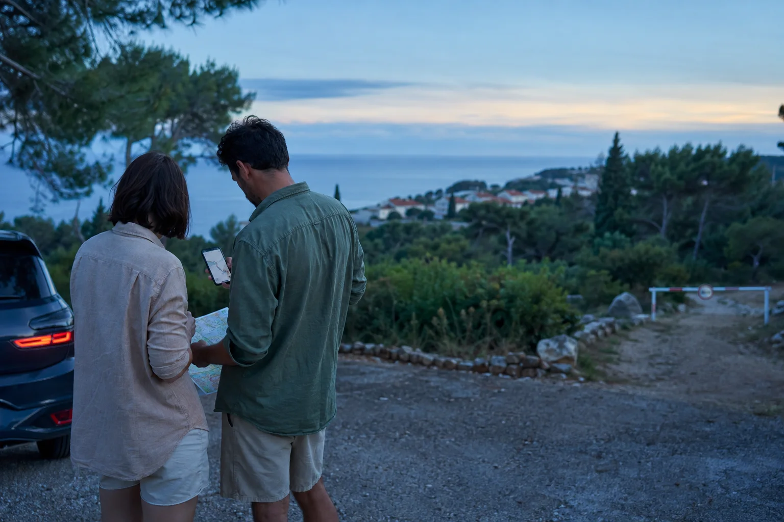 Zwei Reisende prüfen vor einer Abendfahrt bei Rovinj ihre Route auf Karte und Smartphone