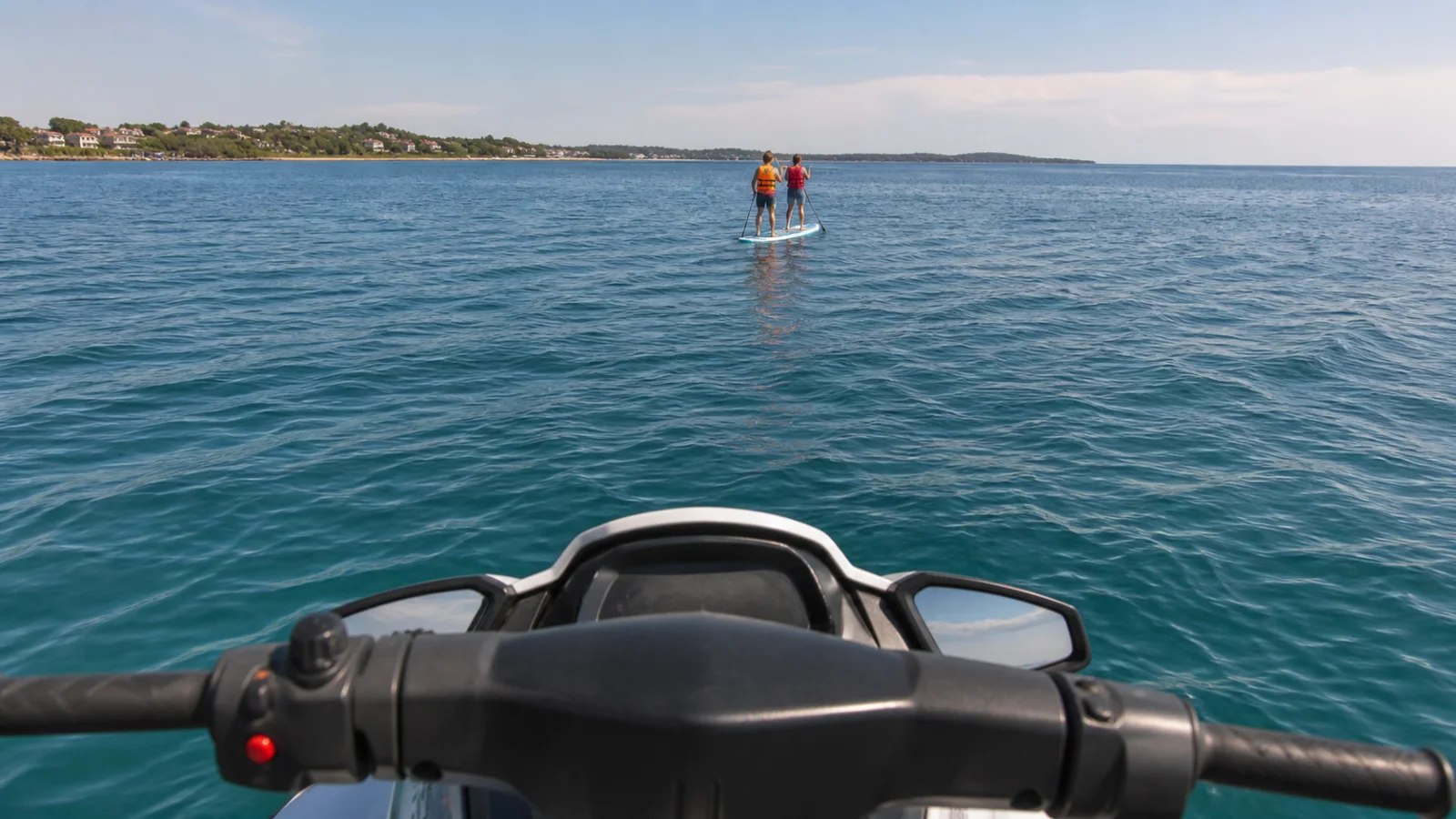 Blick von einem stillstehenden Jet-Ski auf ein weiter entferntes SUP mit zwei gut sichtbaren Paddelnden
