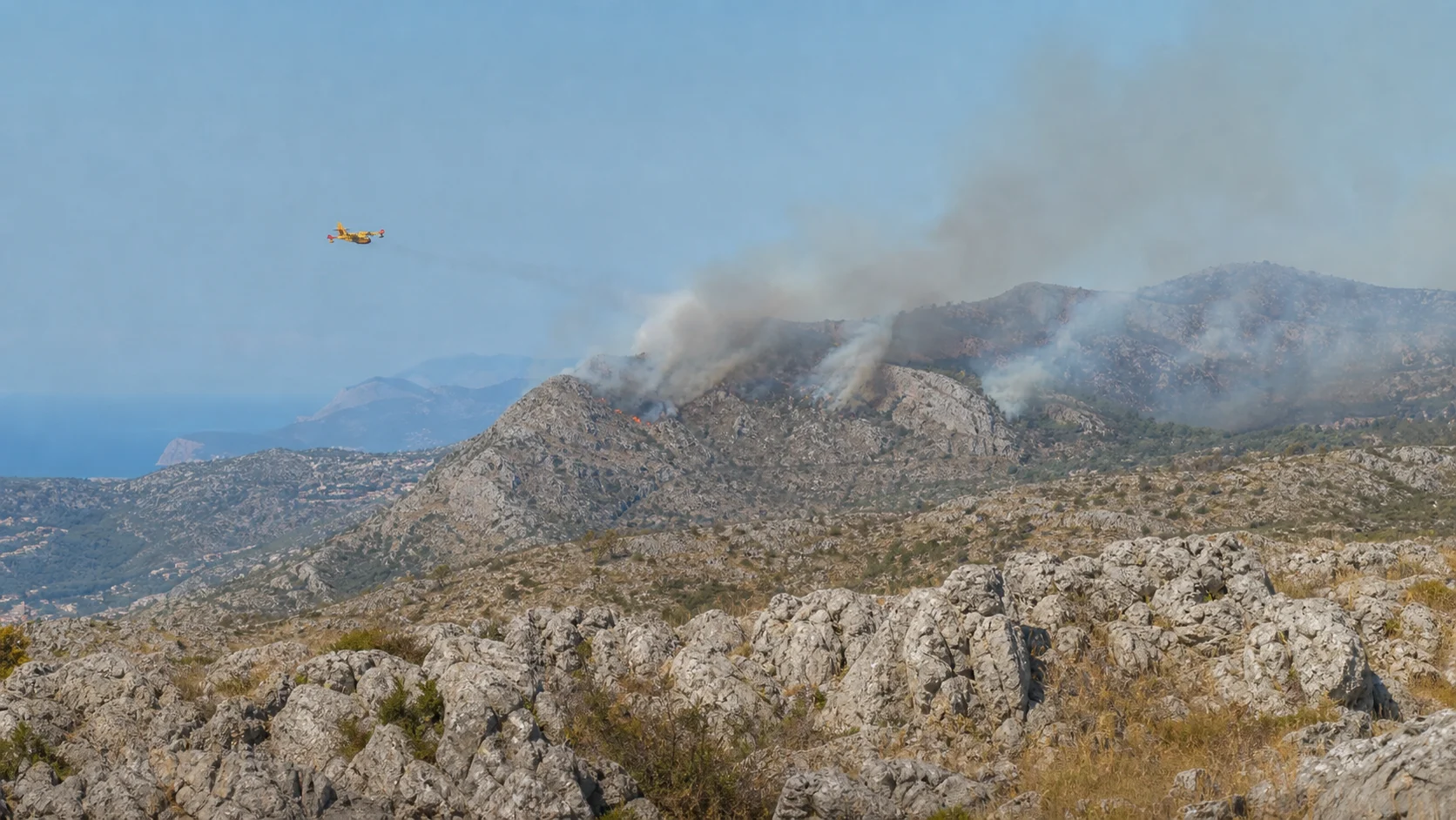 Vegetationsbrand auf abgelegenen Karstgraten oberhalb von Konavle mit einem Löschflugzeug in der Ferne