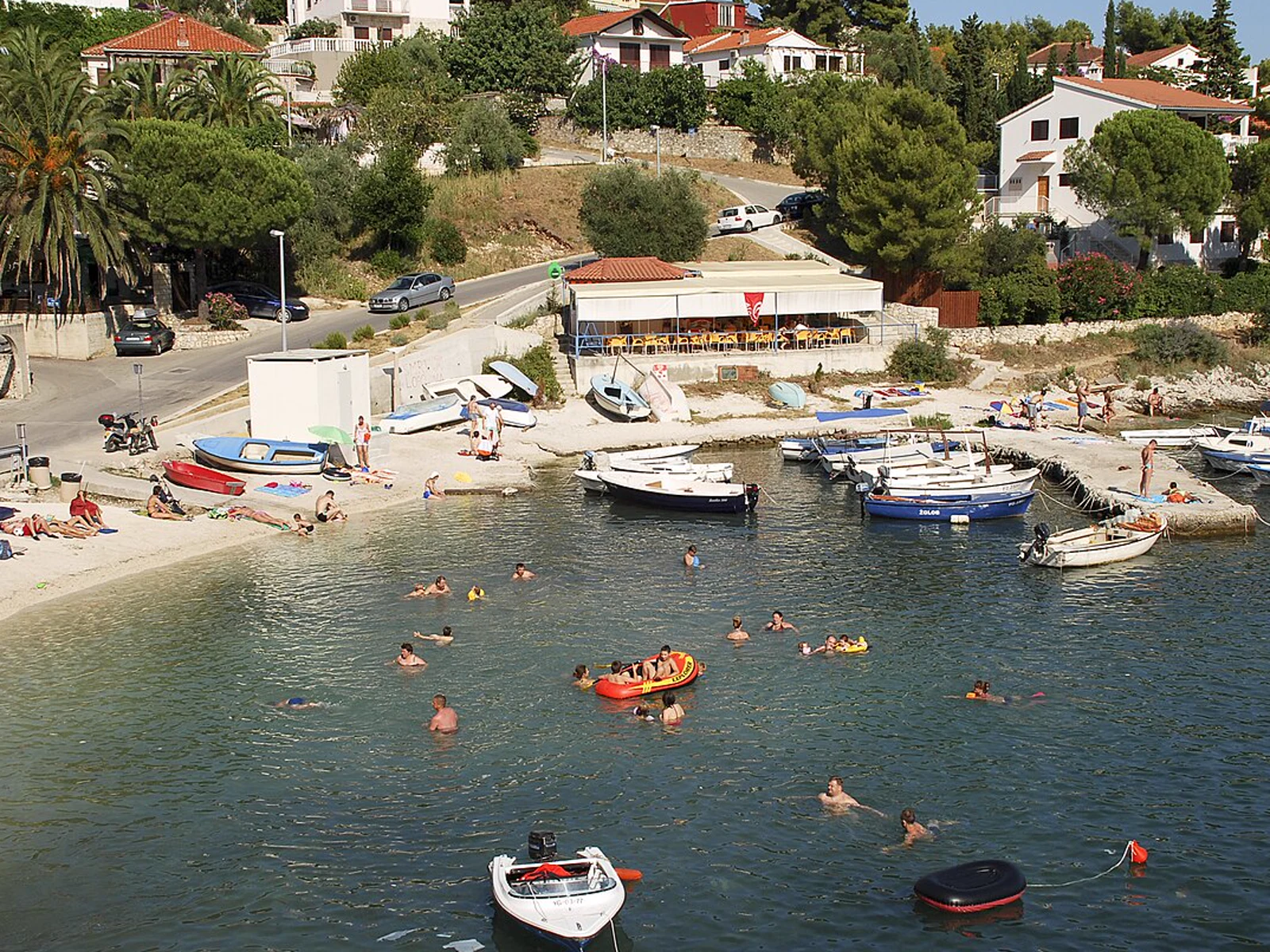 Bucht Mavarčica auf Čiovo mit zahlreichen Badenden und mehreren kleinen Booten nahe dem Ufer