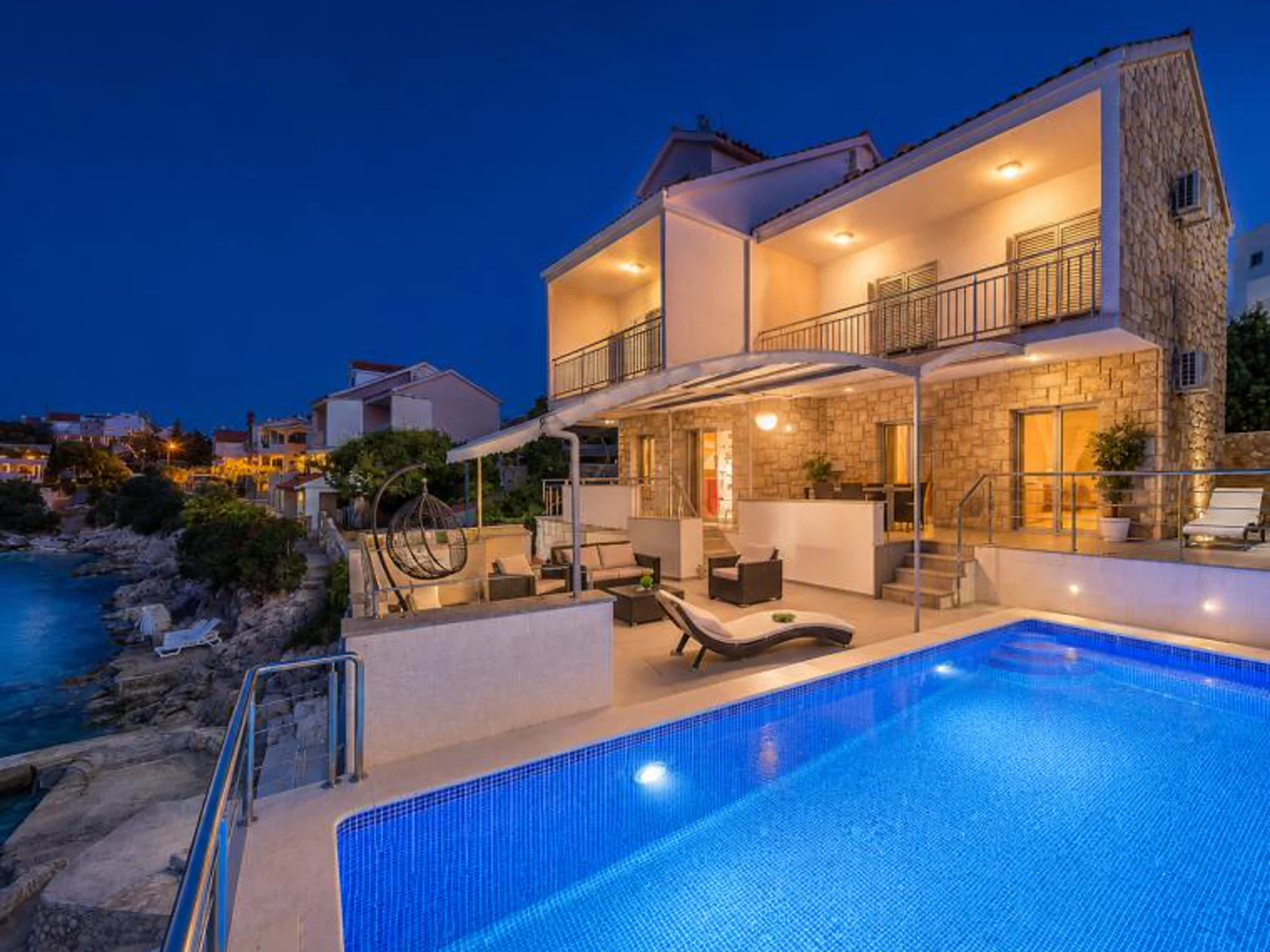 Die beworbene Villa in Ražanj mit beleuchtetem Pool unmittelbar an der felsigen Meeresküste