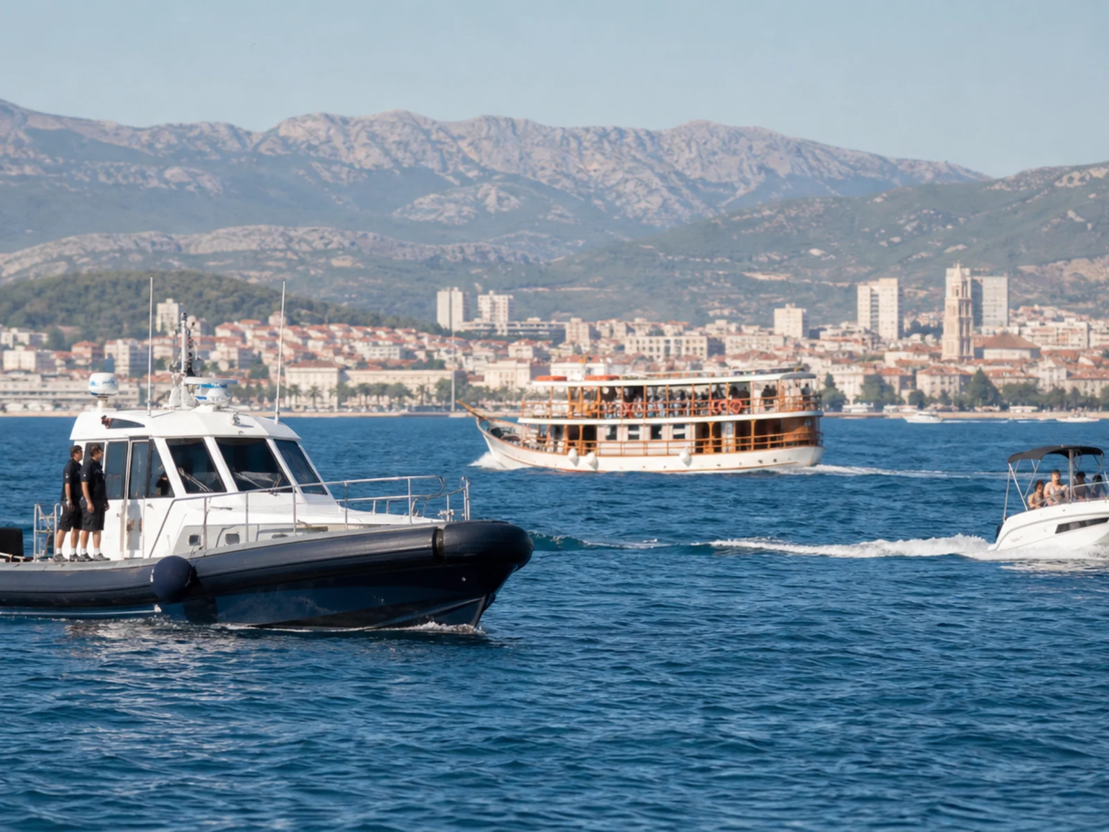 Maritimes Einsatzboot neben einem Ausflugsschiff und Motorboot vor der Küste von Split